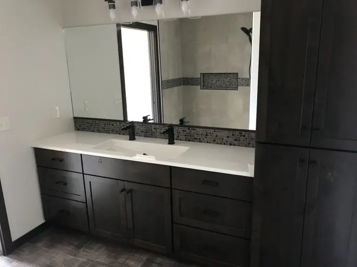 Bathroom with dark wood vanity, double sinks and built-in storage in a custom Redi-Built home