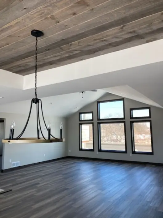 Open living and dining area with vaulted ceiling and wood ceiling accent in a custom Redi-Built home