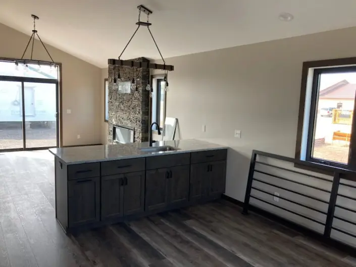 Open-concept kitchen wood island and stone fireplace in a custom Redi-Built home