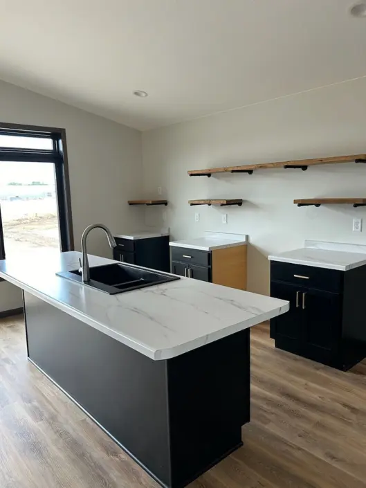 Custom kitchen with black island, wood accent cabinetry and floating shelves in a Redi-Built home