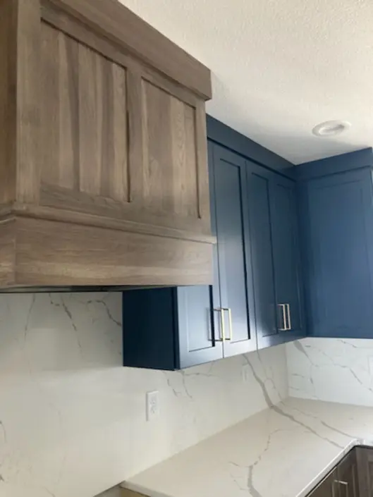 Custom kitchen with blue and wood cabinetry and marble-look countertops in a Redi-Built home